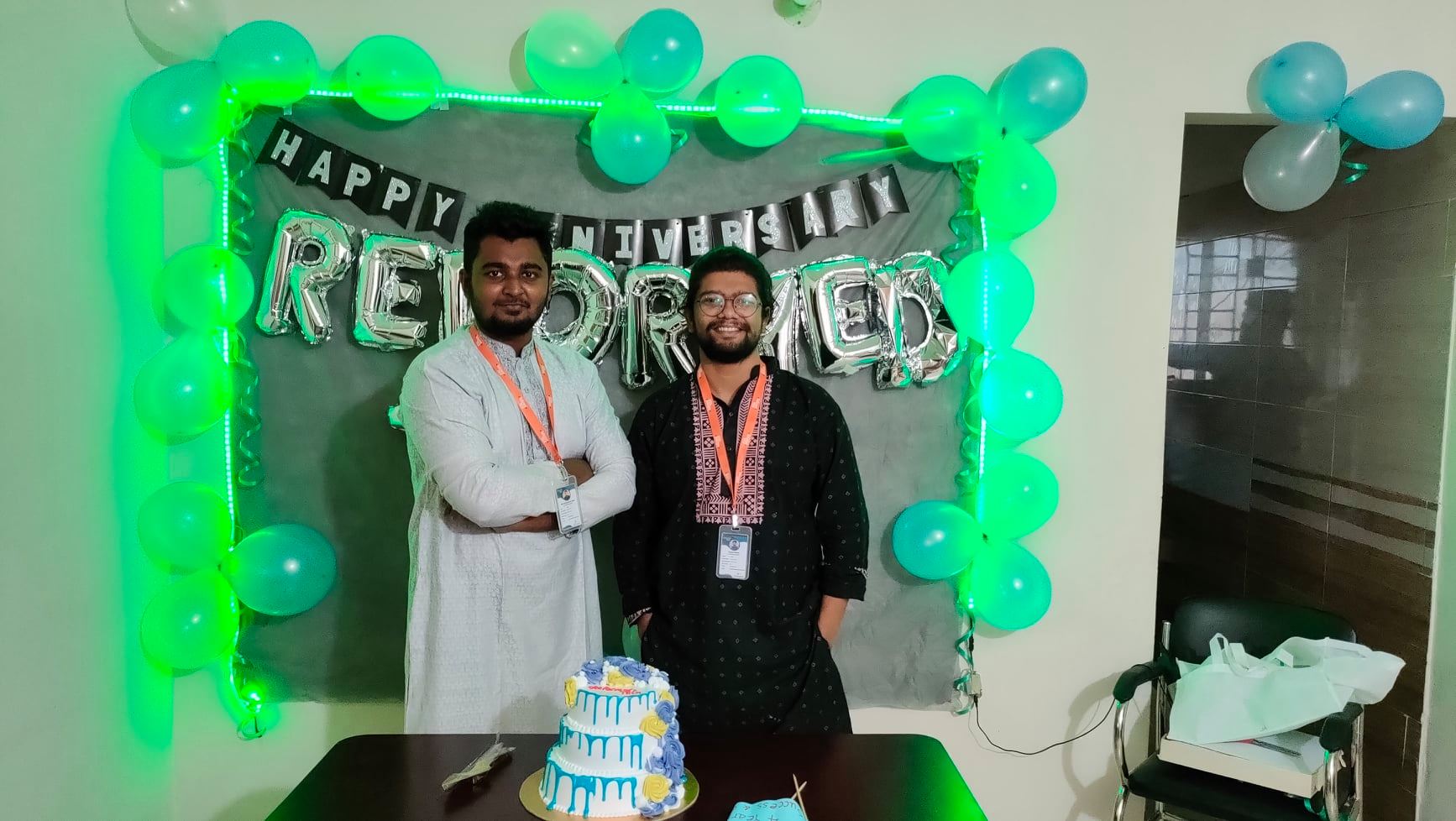 Two people standing infront of Reformedtech anniversary decoration